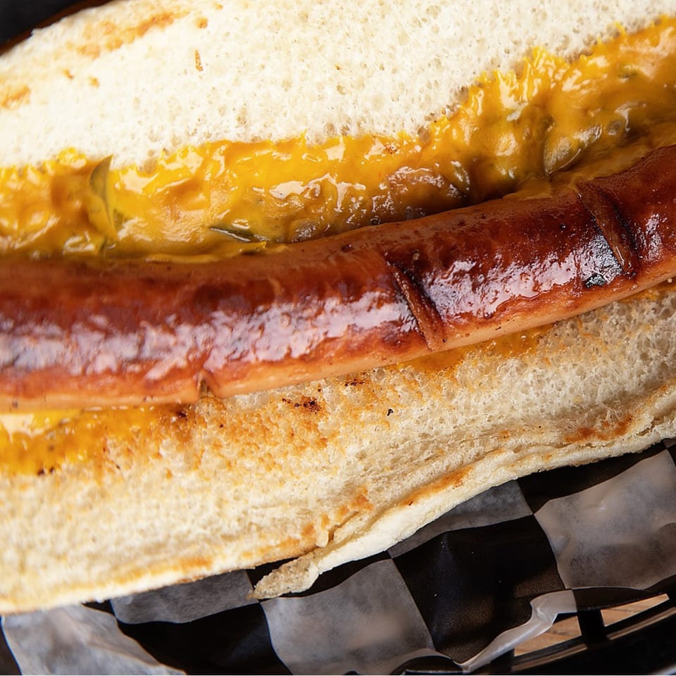 Close-up of a Kirt's Drive-In hot dog with mustard in a toasted bun.